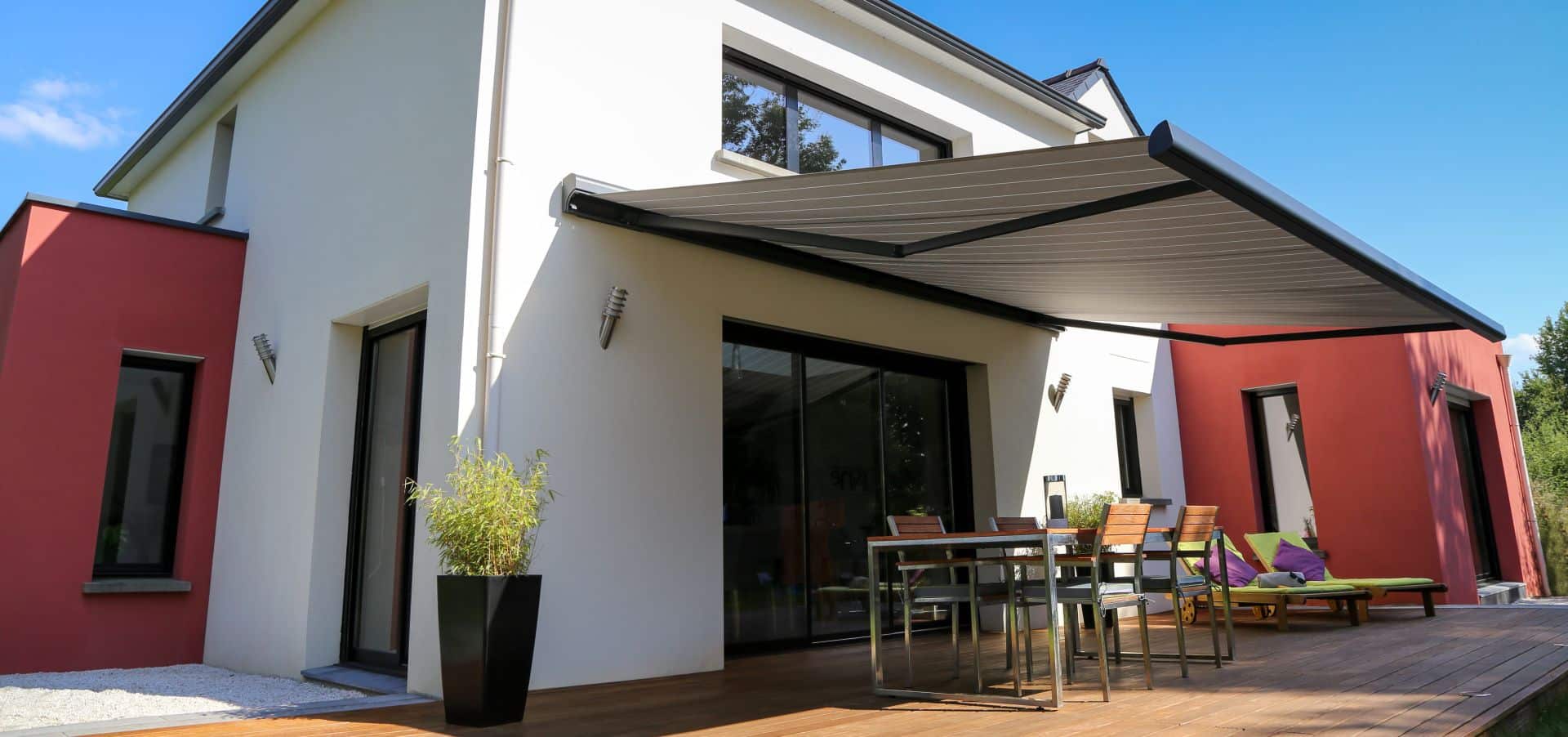 Modernes Einfamilienhaus mit großer ausgefahrener Terrassenmarkise.
